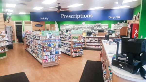 aisles filled with products and the pharmacy counter in a pharmacy store