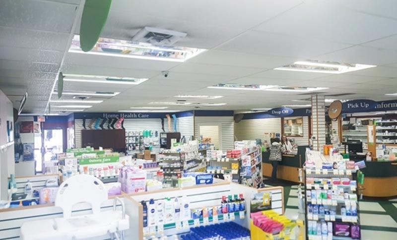 aisles filled with products in a pharmacy store with a pharmacy counter